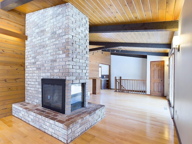 unfurnished living room featuring a brick fireplace, light hardwood / wood-style floors, wooden ceiling, and wood walls