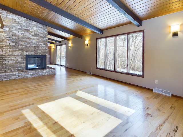 unfurnished living room with wooden ceiling, lofted ceiling with beams, a brick fireplace, and light wood-type flooring