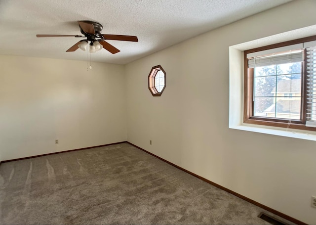 carpeted empty room with ceiling fan, plenty of natural light, and a textured ceiling