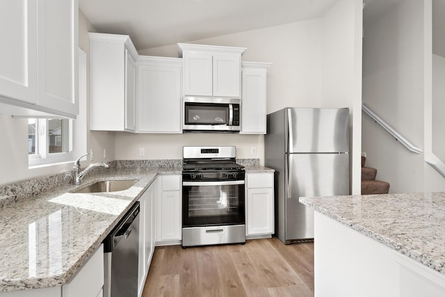 kitchen featuring light stone counters, sink, stainless steel appliances, and white cabinets