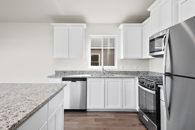 kitchen with dark wood-type flooring, sink, white cabinetry, appliances with stainless steel finishes, and light stone countertops