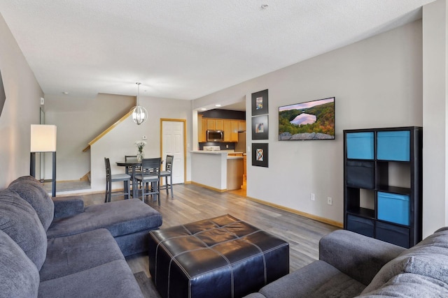 living room with a notable chandelier, light hardwood / wood-style floors, and a textured ceiling