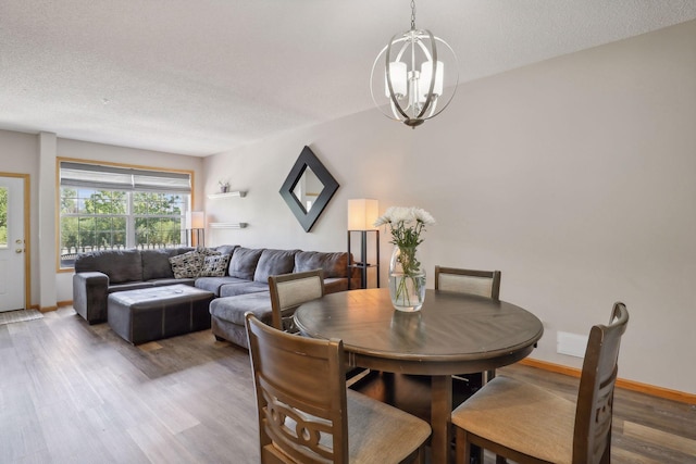 dining area with hardwood / wood-style flooring, a chandelier, and a textured ceiling