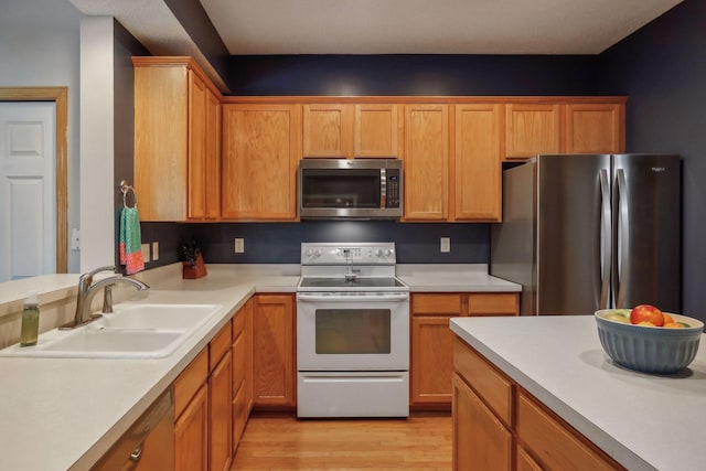 kitchen with stainless steel appliances, sink, and light wood-type flooring