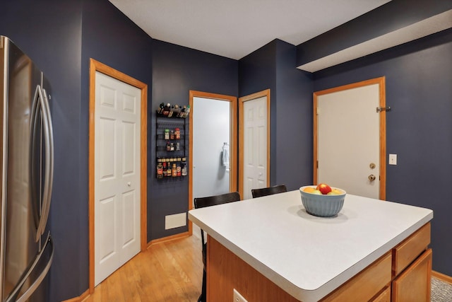 kitchen with a center island, stainless steel fridge, and light hardwood / wood-style floors