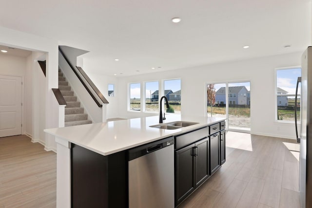 kitchen featuring appliances with stainless steel finishes, sink, a kitchen island with sink, and light hardwood / wood-style floors