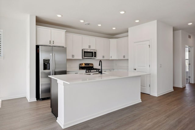 kitchen with sink, light hardwood / wood-style flooring, a kitchen island with sink, stainless steel appliances, and white cabinets