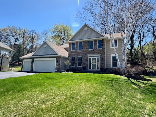 colonial inspired home featuring a front yard, a garage, stone siding, and aphalt driveway