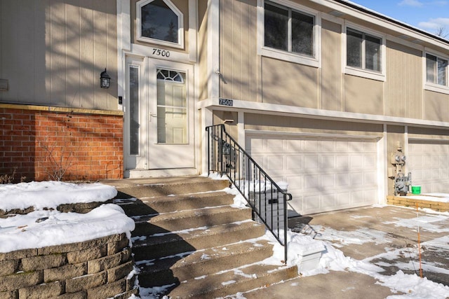 snow covered property entrance featuring a garage