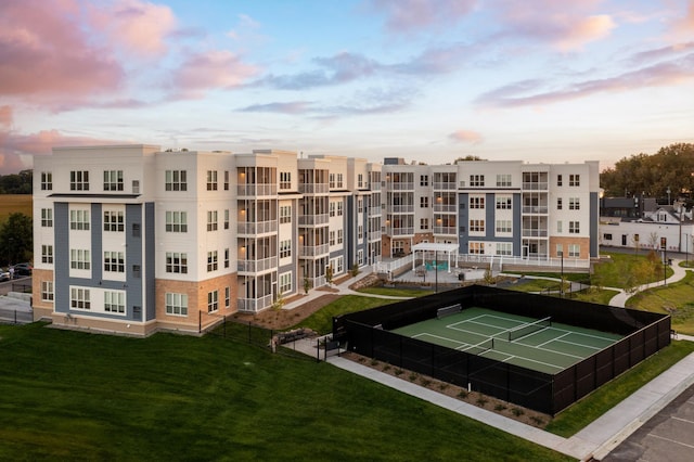 view of property's community featuring a yard and tennis court