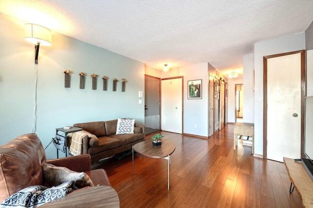 living area featuring a textured ceiling, baseboards, and wood finished floors