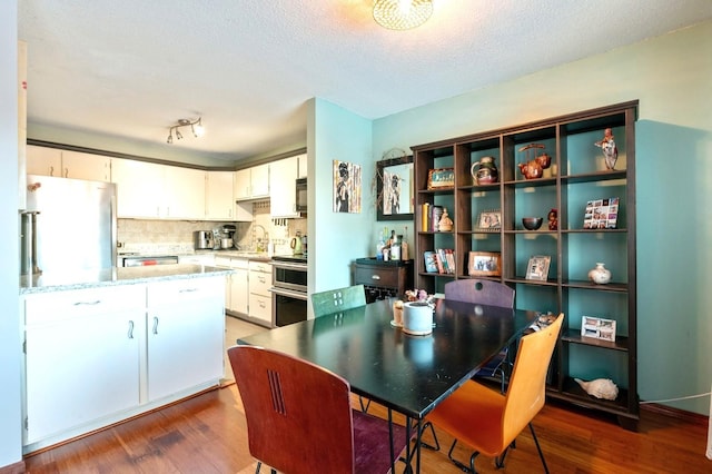 kitchen featuring light stone counters, wood finished floors, white cabinetry, appliances with stainless steel finishes, and tasteful backsplash