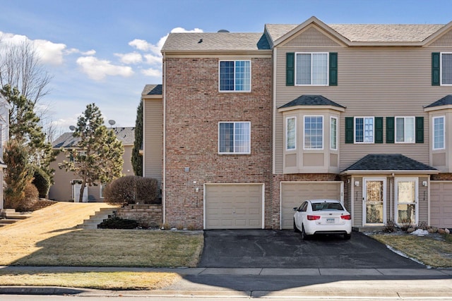 townhome / multi-family property featuring driveway, a garage, and brick siding