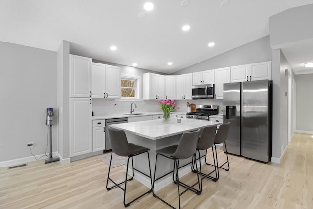 kitchen with white cabinetry, sink, a breakfast bar area, a center island, and stainless steel appliances