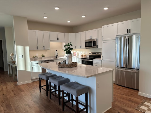 kitchen featuring sink, a breakfast bar, white cabinetry, stainless steel appliances, and a kitchen island