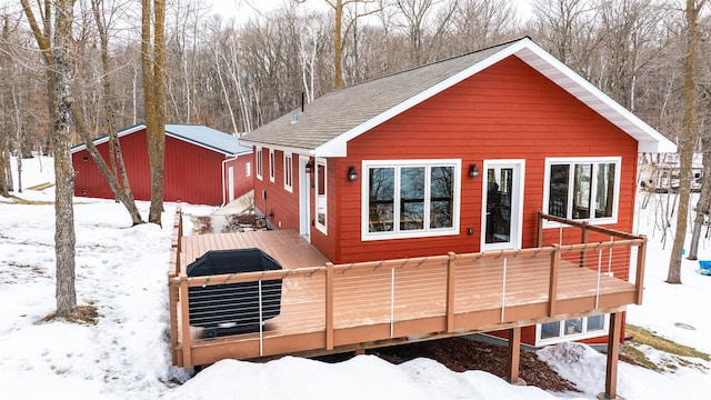 snow covered property with roof with shingles and a wooden deck