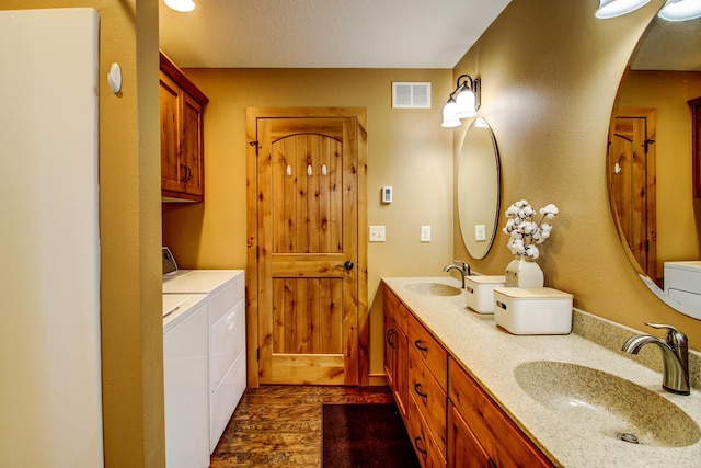 bathroom with a sink, visible vents, washing machine and dryer, and double vanity