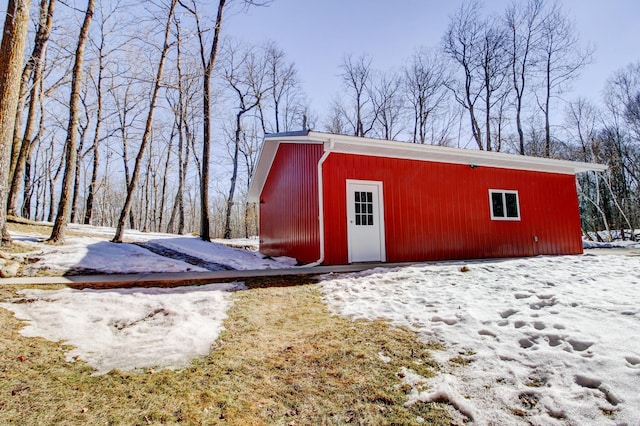 snow covered structure with an outbuilding