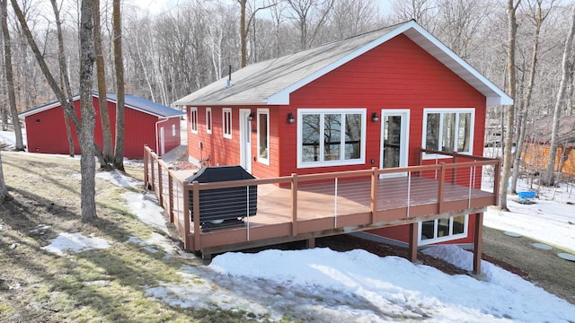 exterior space featuring a deck, an outdoor structure, and a shingled roof