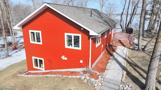 view of property exterior with a deck and roof with shingles