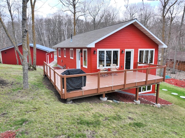 rear view of property featuring a lawn, a shingled roof, and a deck