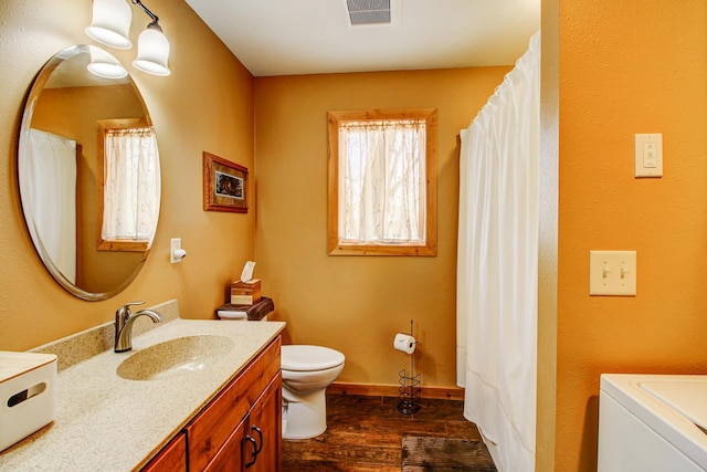 full bath featuring visible vents, vanity, washer / dryer, wood finished floors, and toilet