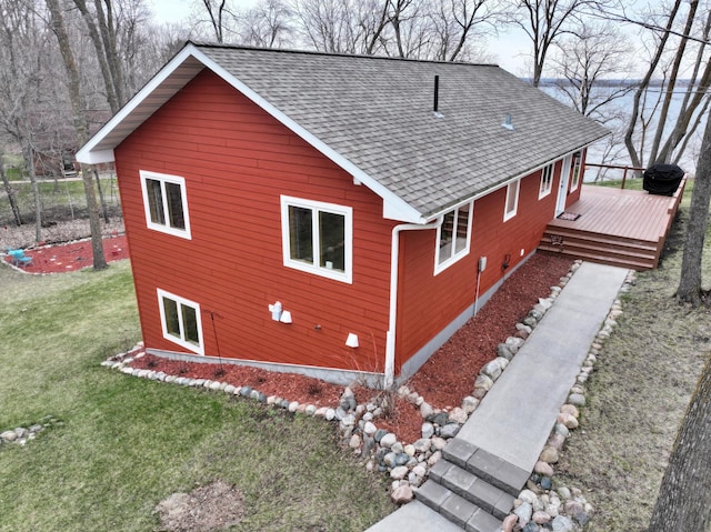 view of side of property with a shingled roof, a yard, and a deck