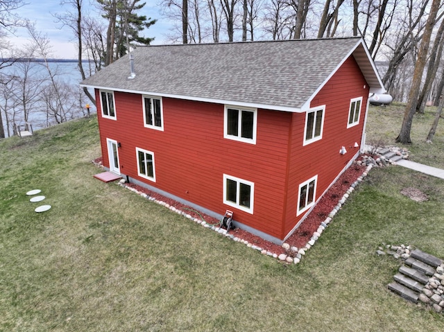 view of home's exterior with a lawn and a shingled roof