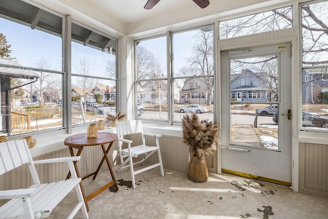 sunroom / solarium with a ceiling fan and a residential view