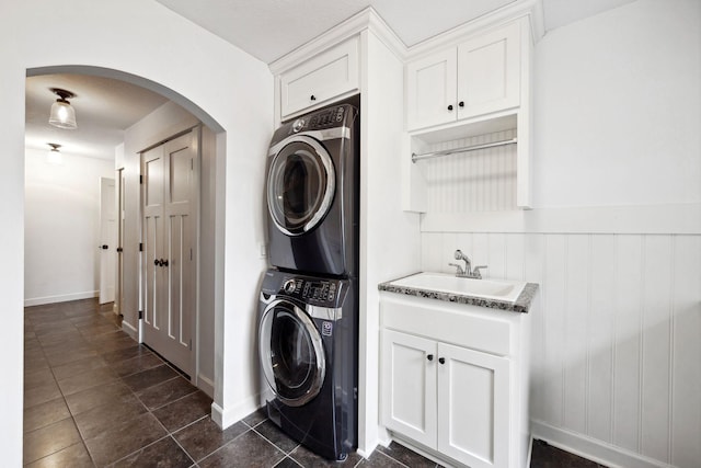 2650 Fox St, Orono, MN 55391 - laundry area featuring stacked washer and clothes dryer, arched walkways, dark tile patterned floors, wainscoting, and baseboards