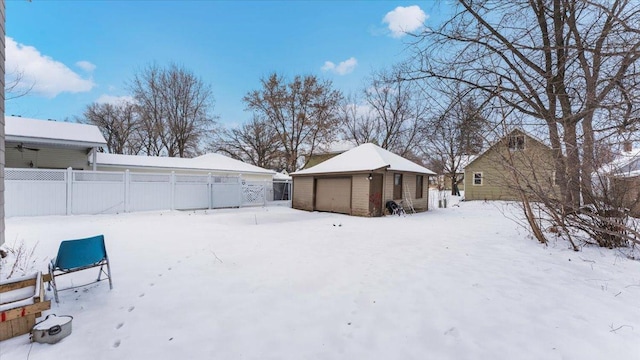 yard covered in snow featuring a garage and an outdoor structure