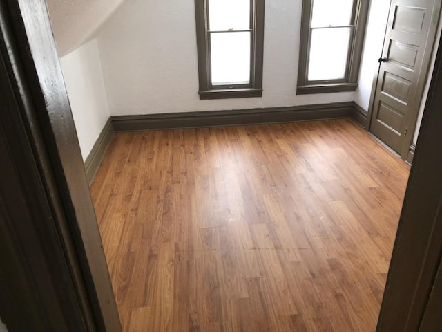 additional living space with lofted ceiling and light wood-type flooring