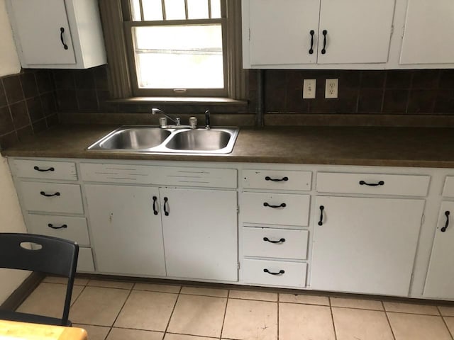 kitchen featuring tasteful backsplash, sink, light tile patterned floors, and white cabinets