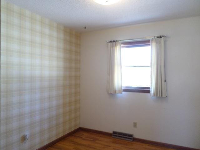 empty room with dark hardwood / wood-style floors and a textured ceiling