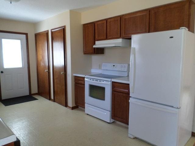 kitchen featuring white appliances, light floors, brown cabinetry, under cabinet range hood, and light countertops