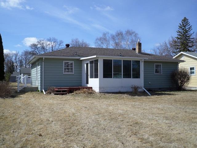 rear view of property with a sunroom, a chimney, and a lawn