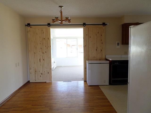 kitchen featuring an inviting chandelier, freestanding refrigerator, a barn door, fridge, and wood finished floors