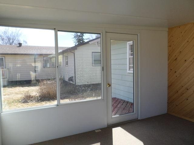 doorway featuring wood walls and carpet