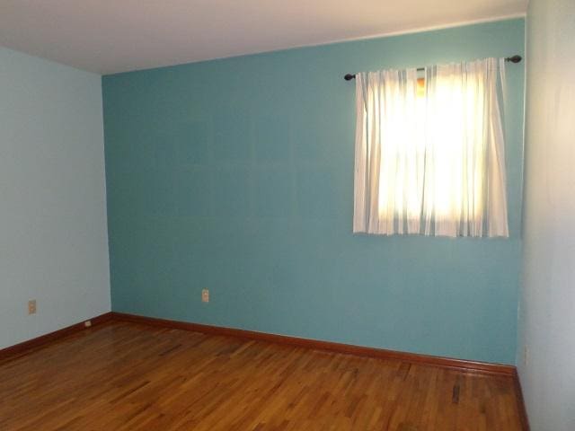 unfurnished room featuring baseboards and wood finished floors