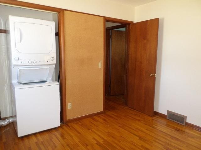 washroom with visible vents, laundry area, wood finished floors, and stacked washer and clothes dryer