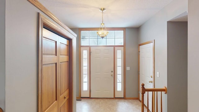 entryway with a wealth of natural light, a textured ceiling, and an inviting chandelier