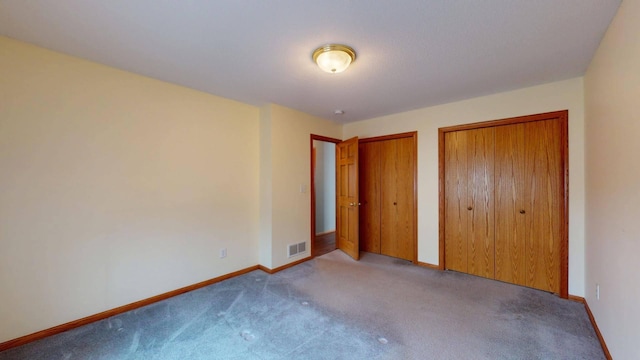 unfurnished bedroom with light colored carpet and two closets