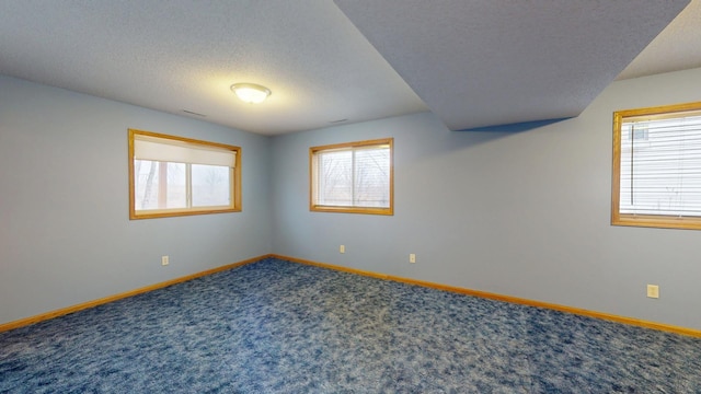 carpeted spare room with plenty of natural light and a textured ceiling