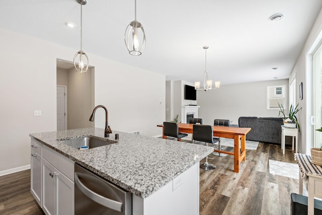 kitchen with white cabinetry, an island with sink, sink, hanging light fixtures, and stainless steel dishwasher