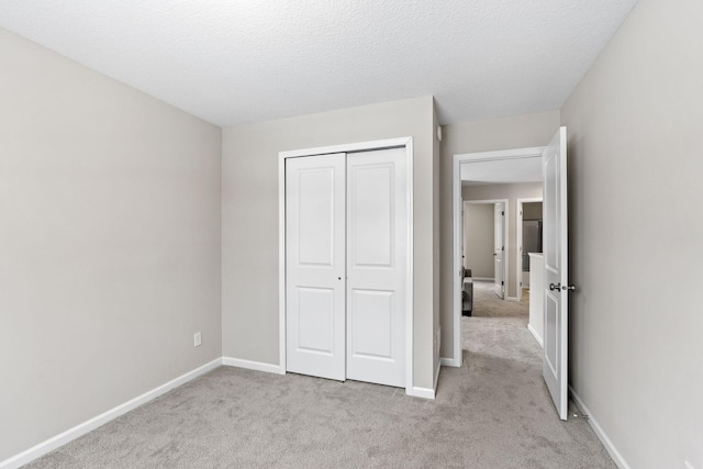 unfurnished bedroom with light colored carpet, a closet, and a textured ceiling