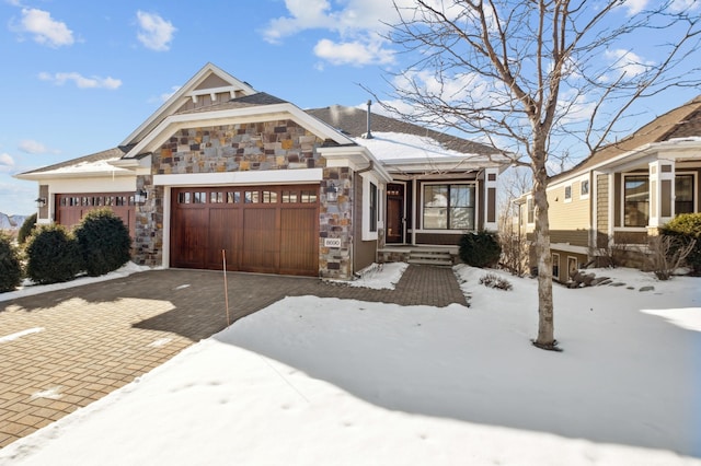 view of front of property featuring a garage, stone siding, and driveway