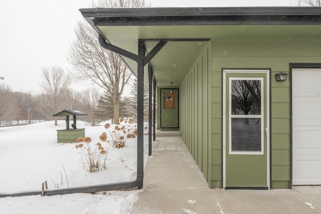 snow covered property entrance featuring a garage