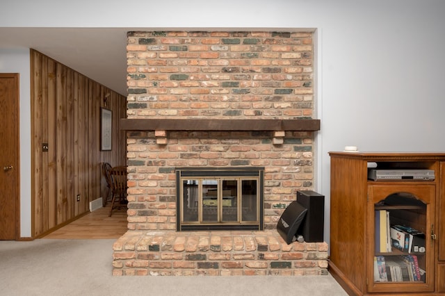 interior details featuring carpet floors, a brick fireplace, and wood walls