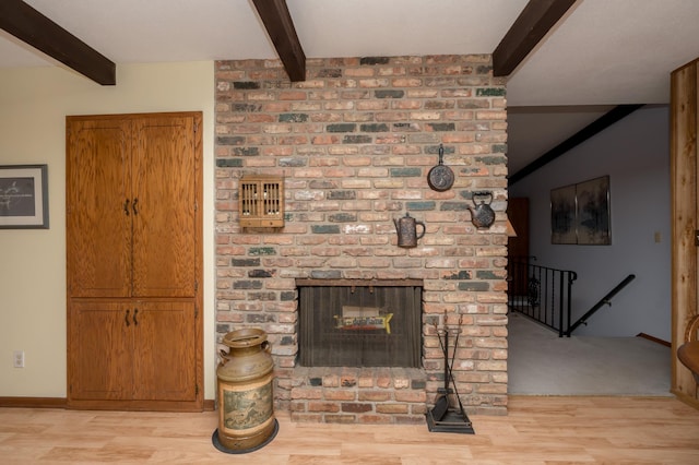 living room featuring a brick fireplace, beam ceiling, and light hardwood / wood-style floors