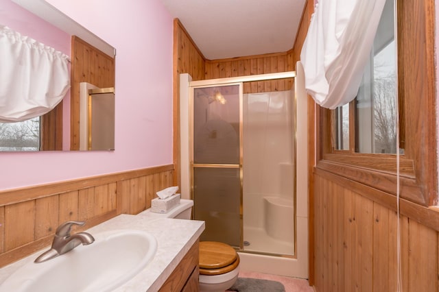 bathroom featuring toilet, vanity, wooden walls, and walk in shower